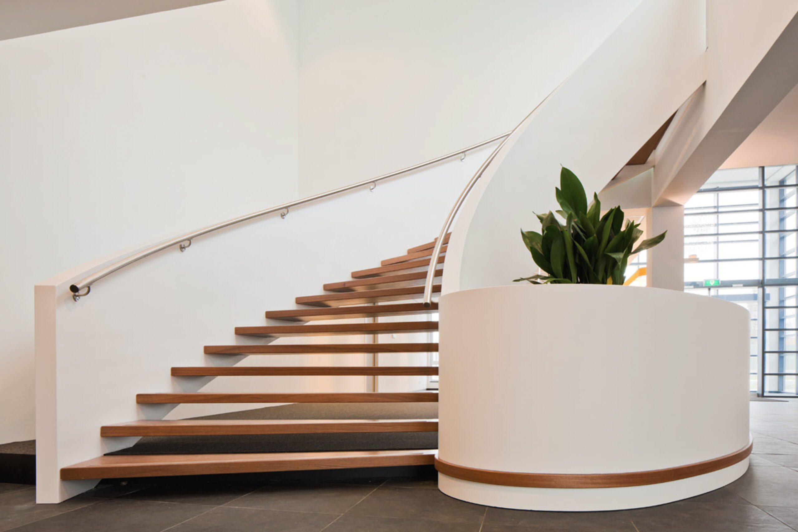 Ruime trap met houten treden en plant in kantoor