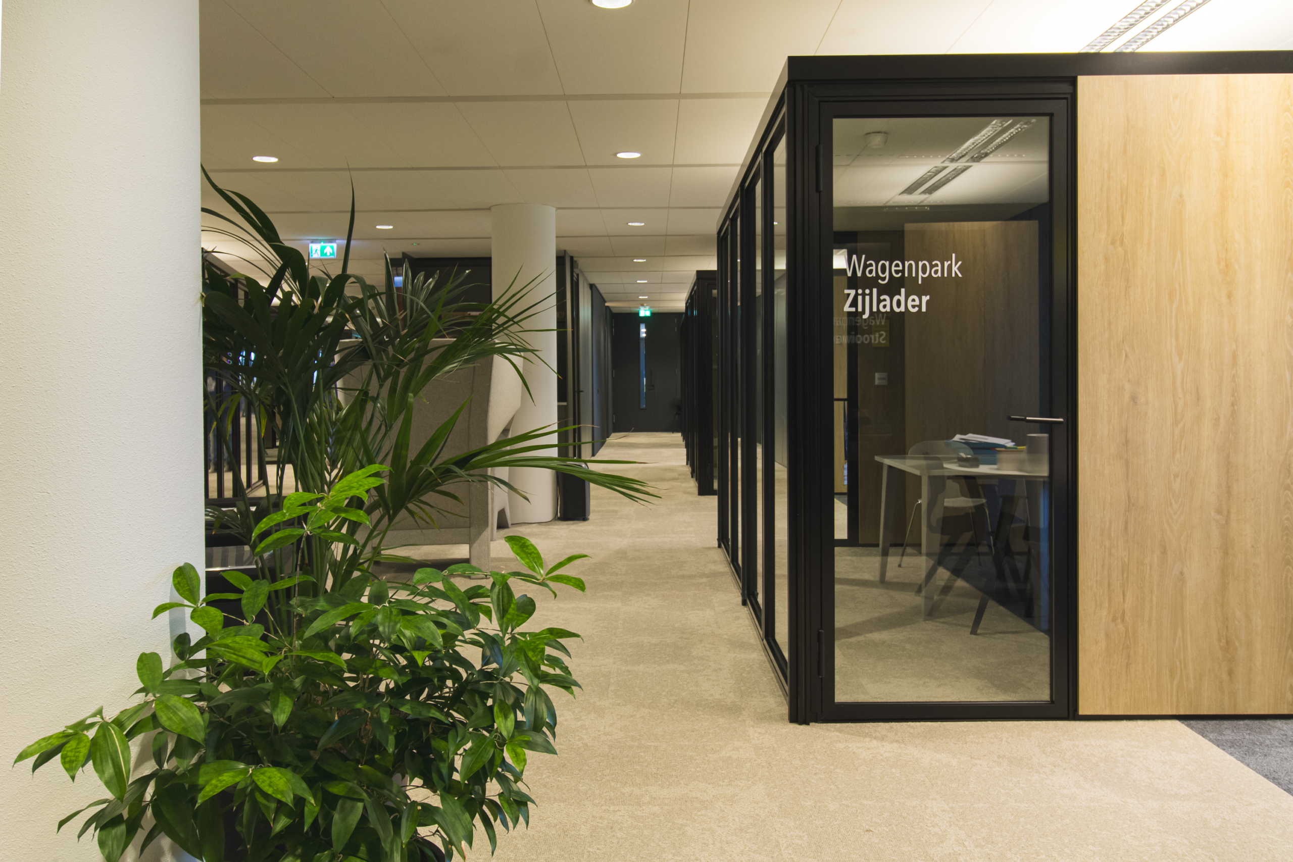 Kantoorgang met planten en een houten vergaderbox