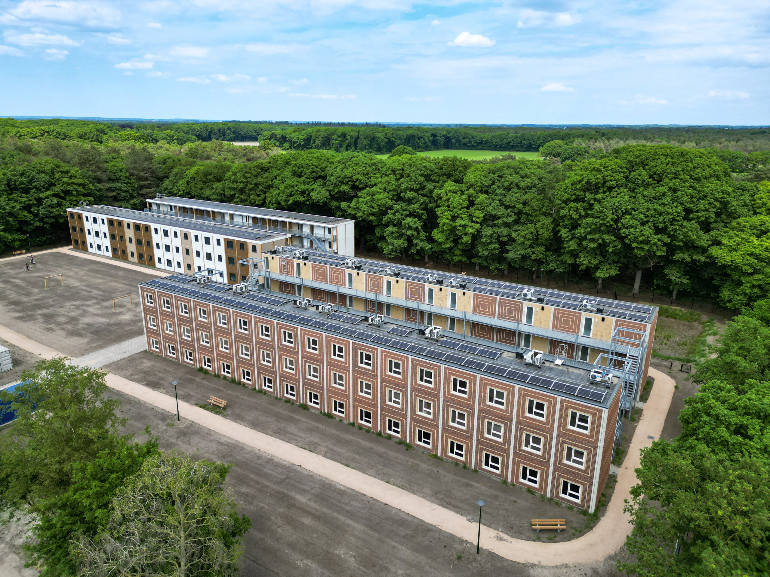 Luchtfoto van een opvanglocatie met woonunits in het bos