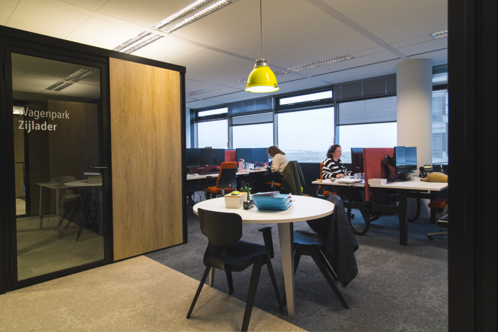 Werkruimte met ronde tafel naast een houten vergaderbox