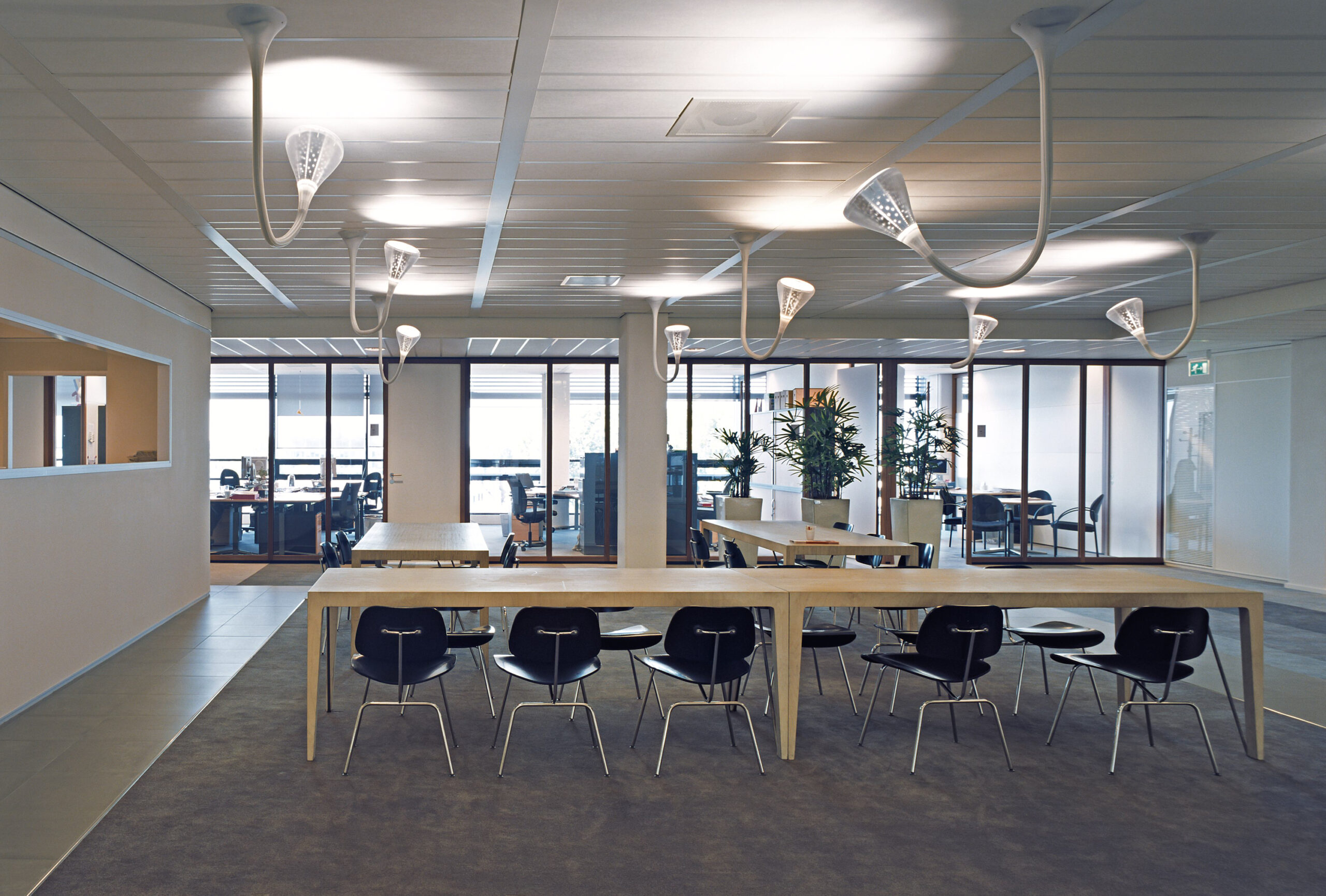 Open kantoorverdieping met lange tafel en zwarte stoelen