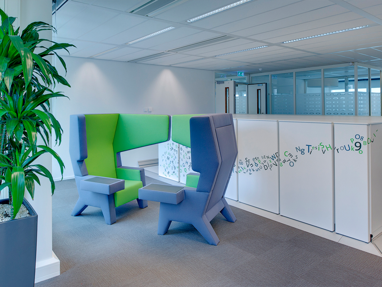 Zithoek met groene en blauwe fauteuils naast een plant