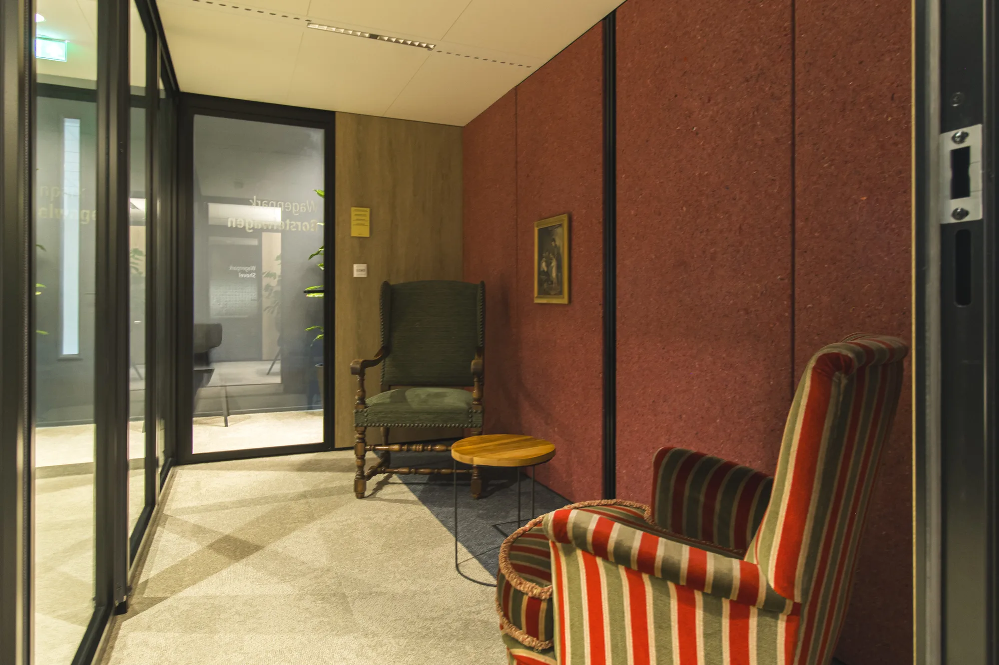 Besloten zithoek met rode wand en gestreepte fauteuil