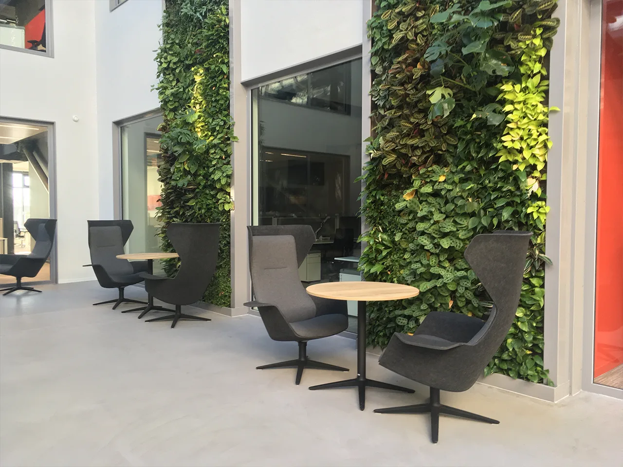 Groenwand met fauteuils en statafel